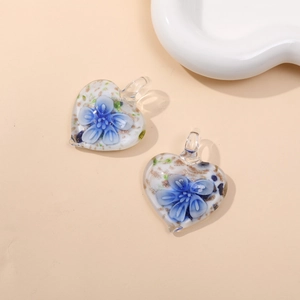 Macro view of heart-shaped glass pendants with blue flower patterns and golden glitter
