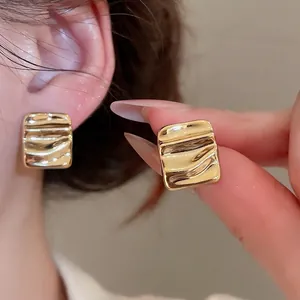 Square wavy metal stud earrings in gold finish featuring a textured surface for women