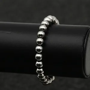 Polished stainless steel beaded bracelet for men and women on a black display stand
