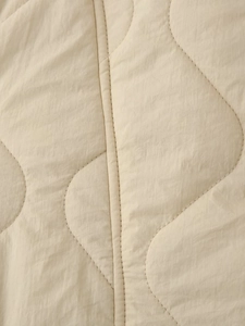Close-up of beige quilted fabric featuring elegant wavy stitching and detailed texture