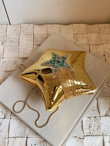 Macro detail of gold star acrylic clutch with rhinestone fringe and fine chain strap