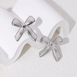 Fashionable silver stainless steel bow earrings with striped texture on a wavy stand
