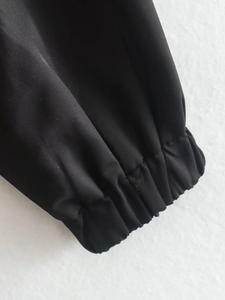 Detail view of durable black bomber jacket showing elastic ribbed cuffs and woven fabric