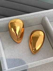 Macro detail of high-polish 18k gold teardrop earrings on a velvet display tray