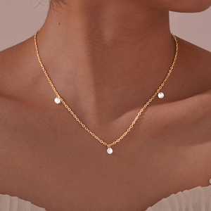 Close-up of golden necklace with three white zircons worn on a model's neck