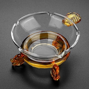 Clear glass tea filter with amber leaf detail and carved animal head feet support