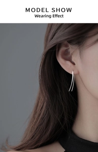 Close-up of minimalist silver double-line curved earrings worn by a model