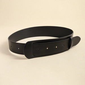 Detail of wide black leather corset belt with gold studs on a neutral beige background