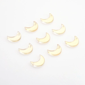 Flat lay of nine crescent moon glass charms with gold glitter for DIY jewelry making