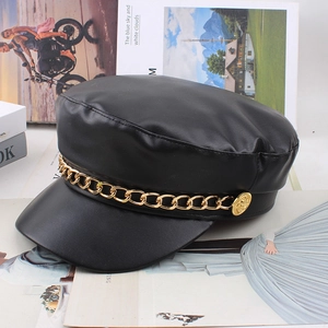 Detailed macro view of black PU leather baker boy hat with golden metal chain ornament