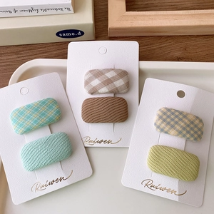 Detailed view of macaron plaid and solid fabric hair clips on branded display cards