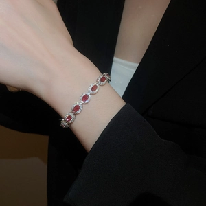 Gros plan d'un bracelet en argent avec zircons rouges ovales sur un poignet féminin