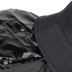 Texture contrast between glossy patent leather and matte twill fabric on black bucket hat