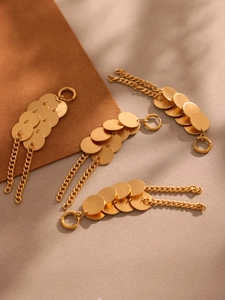Détail de boucles d'oreilles dorées en acier avec disques superposés et chaînes