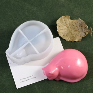 Silicone mold with a finished pink sleeping cat resin pen holder on a green textured surface
