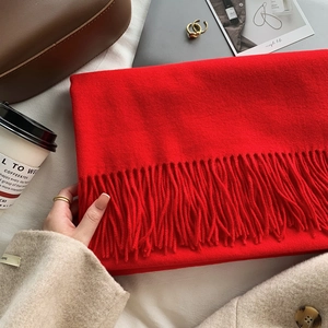 Detail of red winter knit scarf with soft tassel fringe and cozy fabric texture