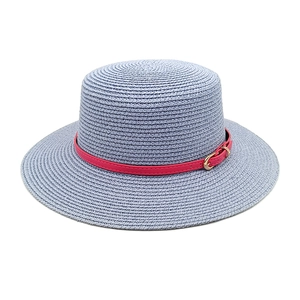 Detail of blue woven straw flat top hat with a red leather band and gold metal buckle
