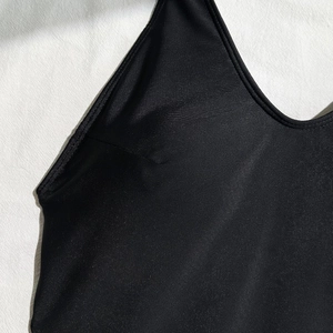 Close-up of black V-neck ribbed swimsuit fabric with detailed stitching on white linen