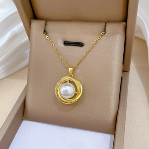 Detail of gold rotating nest pendant with pearl and zircon inlay on jewelry box