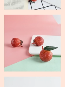 Macro shot of realistic PVC lychee model with textured red skin and green leaves