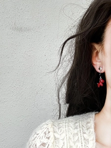 Detail of red pony earrings with silver star studs worn on model for a stylish look