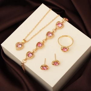 Detail of gold jewelry set featuring pink heart crystals on a white pedestal display