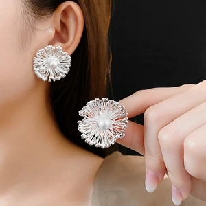 Close-up of a silver flower pearl earring with radiant petals worn on a model's ear