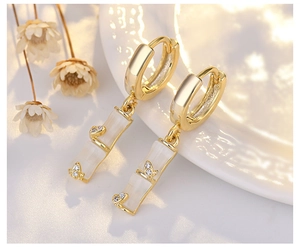 Close-up of gold bamboo drop earrings with milky white stones and sparkling zircon accents