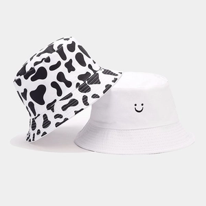 Detail showing cow print pattern and smiley face embroidery on cotton bucket hats