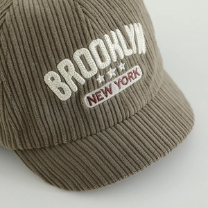 Nahaufnahme der Oliven-Feincord-Struktur und Brooklyn-Stickerei auf der Baby-Mütze