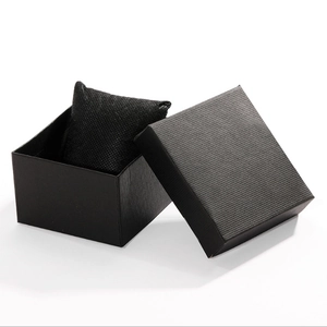 Detail of an open black textured gift box with a matching watch pillow on white background
