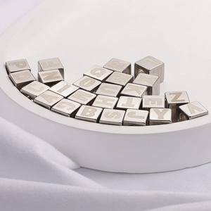Silver stainless steel alphabet cube beads for DIY jewelry making displayed on a tray