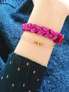 Stacked layered look featuring a pink glitter woven bracelet and a gold tennis bracelet