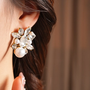 Close-up of vintage gold teardrop earrings with crystal rhinestones and pearls on model