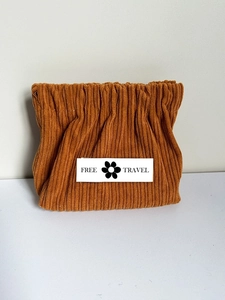 Detail of caramel corduroy makeup pouch with Free Travel label and drawstring closure