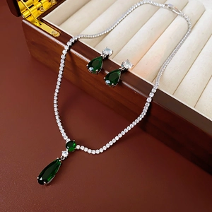 Detail of silver drop necklace and earrings with emerald green stones in a luxury box