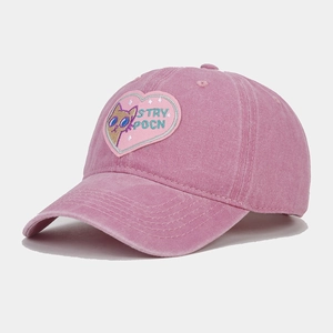 Detailed close-up of a pink washed cotton baseball cap with a cute cat embroidery patch