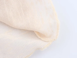 Close-up of beige knitted fabric showing intricate mesh texture and neat stitching details