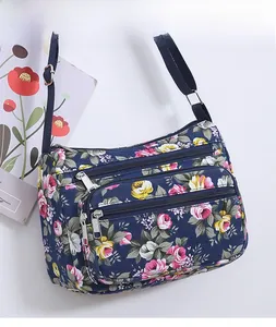 Detail of floral nylon crossbody bag with three front zipper pockets and adjustable strap