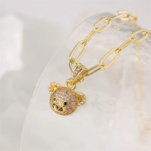 Close-up of teddy bear pendant with pink and black zircon stones on a gold chain necklace