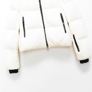 White puffer jacket with cable knit texture, stand collar, and black zipper accents