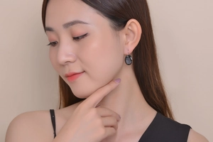 Close-up of elegant black oval gemstone earrings worn by a model in soft studio light