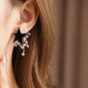 Star-shaped black enamel stud earrings with zircon tassels on a female model