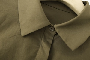 Close-up of the turn-down collar and dark button on this olive green cotton poplin shirt