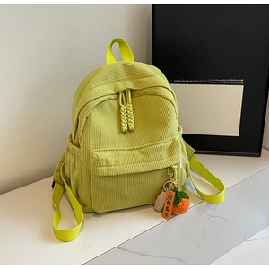 Detail of lime green corduroy backpack with zipper pockets and knitted fruit pendant