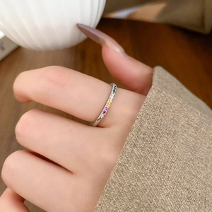 Close-up of a silver band ring featuring vibrant multi-color cubic zirconia rainbow stones