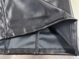 Dettaglio delle doppie cuciture e trama in pelle PU su un abito nero slim fit