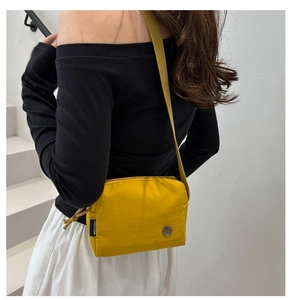 Dettaglio di una borsa a tracolla in nylon giallo acceso con logo M in metallo e tracolla
