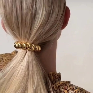 Close-up of a polished gold croissant hair ring accessory on a blonde ponytail
