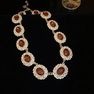 Detailed close-up of gold flower necklace with amber gemstones and white enamel petals